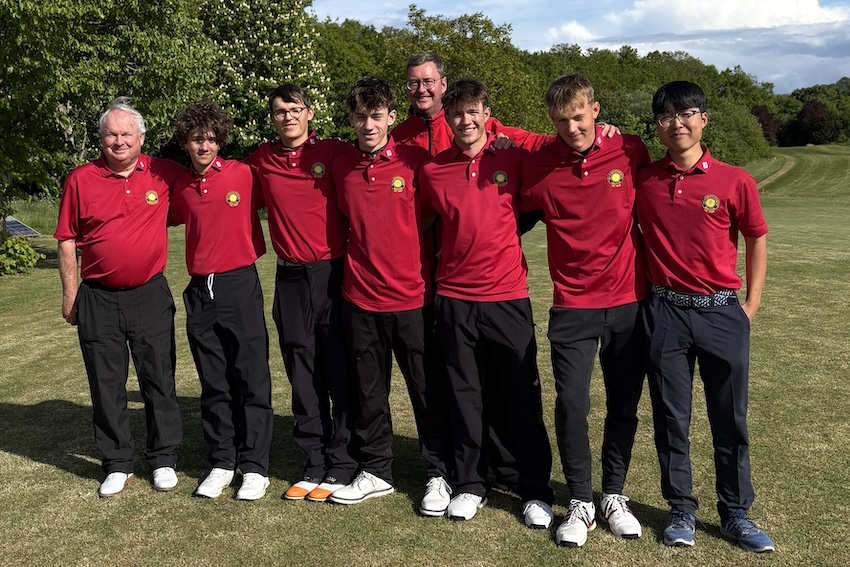 Die Jugendmannschaft des Golfclubs steht gemeinsam mit ihren Trainern auf dem Golfplatz und posiert in roten Teamshirts für ein Gruppenfoto.