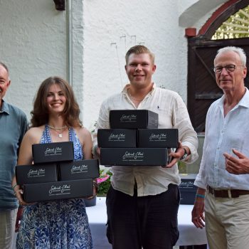 Vier Personen präsentieren bei einer Siegerehrung mehrere Preise des Sponsors Gabriel Glas in den Händen. Die Preisverleihung findet im Innenhof des Golf Club Hof Hausen vor der Sonne statt.