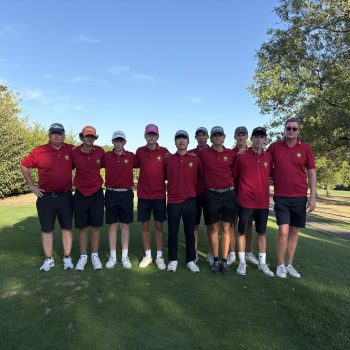„Jugendmannschaft mit Trainern in roten Clubshirts auf einem Golfplatz.“