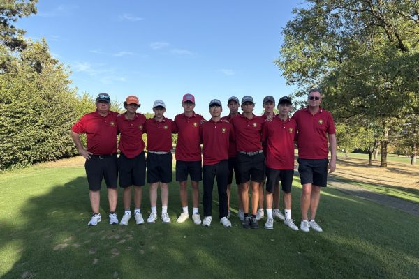 „Jugendmannschaft mit Trainern in roten Clubshirts auf einem Golfplatz.“